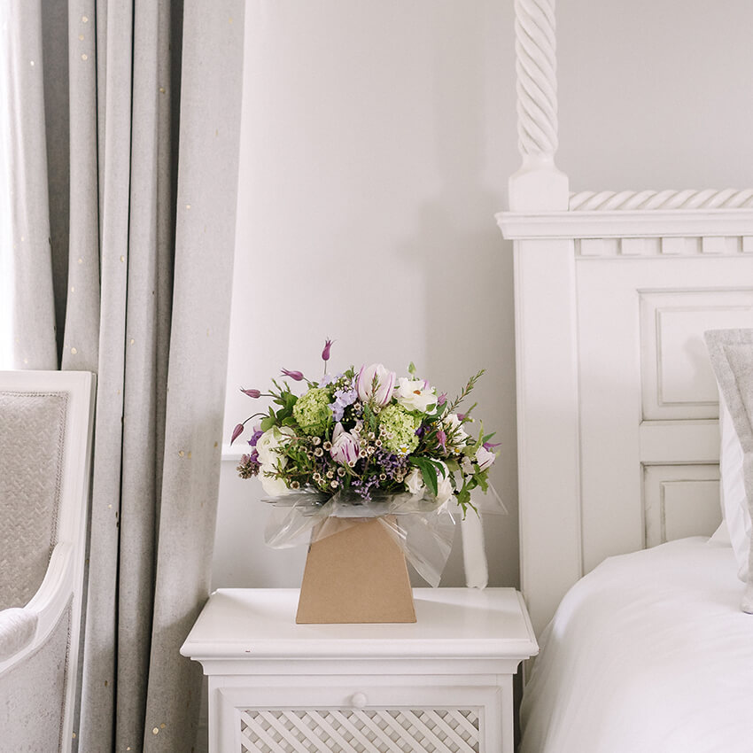 A lush floral arrangement on a white plinth in a wedding venue room, created by The Flower Shed Westerleigh